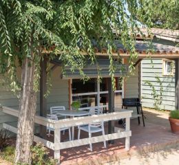 View of a covered terrace with garden furniture and a BBQ in the Premium Bungalows at Camping del Mar 4* in Malgrat de Mar