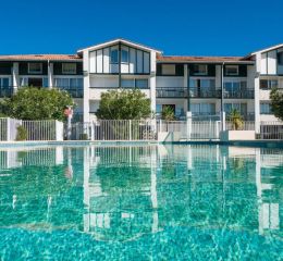 View of the outdoor pool and the Ilbarritz residence in Bidart under a blue sky