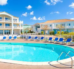 Espace aquatique extérieur entouré de chaises longues et de jardins verdoyants à la résidence l'Estran aux Sables-d'Olonne