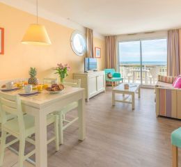 Pièce à vivre aménagée avec télévision et canapé-lit donnant sur un balcon privatif avec vue mer à la résidence l'Estran aux Sables-d'Olonne