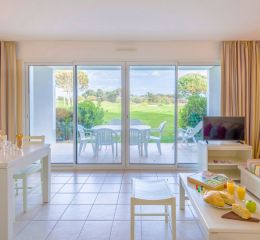 Spacious, fully equipped living room with television and sofa bed opening onto a private outdoor area overlooking the residence’s gardens at the L’Estran residence in Les Sables-d’Olonne