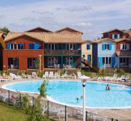 Central heated swimming pool surrounded by clusters of houses in a fisherman’s cabin style at the Les Rives Marines residence in Le Teich