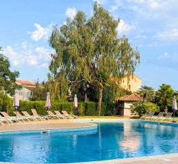 Unheated outdoor swimming pool with sun loungers, surrounded by lush green gardens at the Sognu di Mare residence in Linguizzetta
