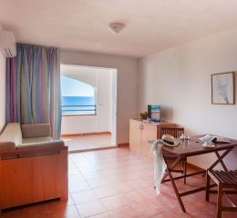 Living room equipped with a television and opening onto a sea-view balcony in one of the apartments at the Sognu Di Rena residence in Moriani-Plage