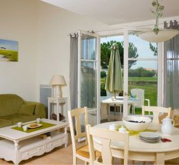 Living room of a Fontenelles house with lounge and dining areas, offering views of and direct access to the golf course