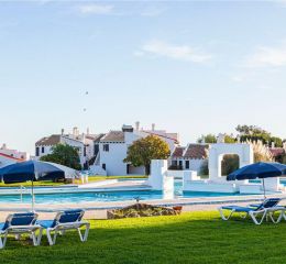 Vue générale de la piscine extérieure non chauffée de Pedras del Rei avec des transats et les logements en fond