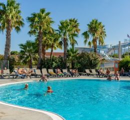 Piscine extérieure avec transats, toboggans et palmiers de la résidence Antinea