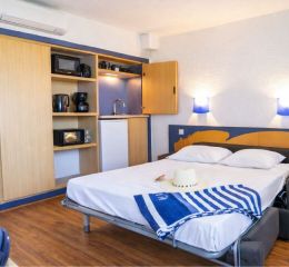 Intérieur d’un studio de la résidence Neptune avec kitchenette et canapé-lit