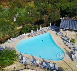 Piscine à débordement en forme de coeur avec chaises longues et parasols et vue sur la mer au camping Lacasa à Calcatoggio