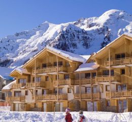 Façade extérieure de la résidence le Parc des Airelles sous la neige avec acces direct aux pistes de ski