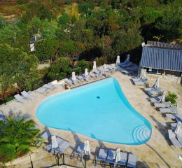 Heart-shaped infinity pool with sun loungers and parasols overlooking the sea at Camping Lacasa in Calcatoggio