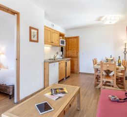 Living room with a kitchen and an adjoining bedroom in the apartments at Les Fermes de Saint Sorlin Residence