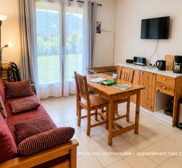 Salon lumineux avec canapé gigogne et télévision dans les appartements de la résidence Le Hameau des Sources à Montbrun-les-Bains