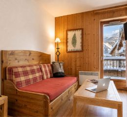 Salon avec cuisine et ouverture sur une chambre dans les appartements de la résidence Les Fermes de Saint-Sorlin