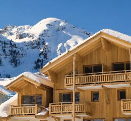 Exterior view of Le Parc des Airelles residence covered in snow, with direct access to the ski slopes