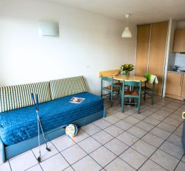 Séjour avec canapé lit et cuisine ouverte équipée d’un studio de la résidence Eugénie à Biarritz