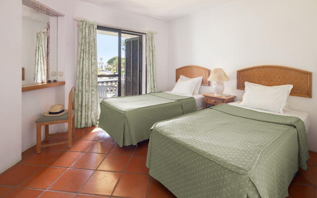 Slide Sleeping area with a twin bedroom in the standard accommodations at Balaia Golf Village