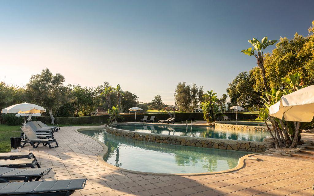 Slide Relaxation area with twin pools, sun loungers, and parasols at Balaia Golf Village