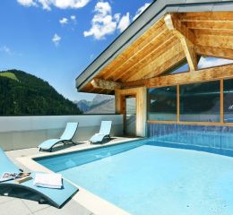 Outdoor pool under the sun at the Le Grand Lodge residence in Châtel